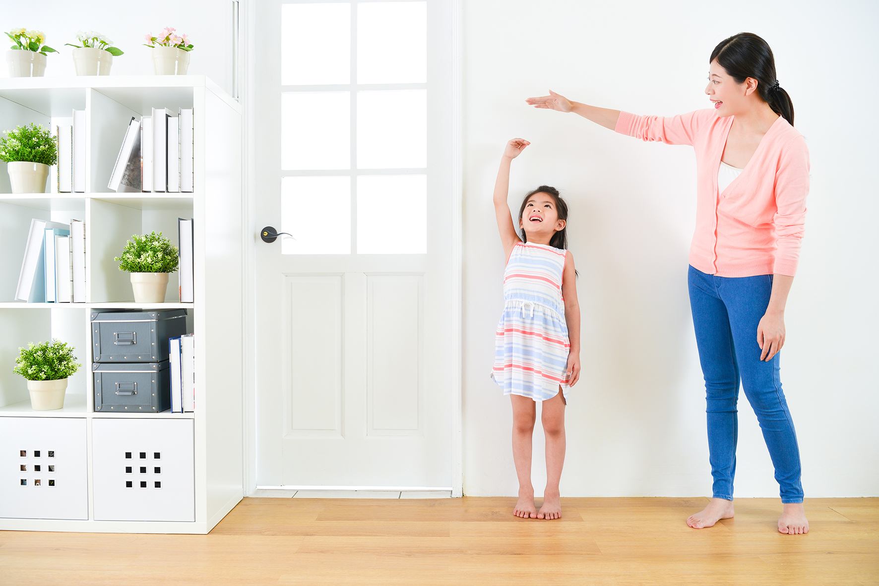 Child height. Детский Stand up. Measuring the growth of a child standing and sitting белый фон. Мальчик измеряет свой рост. Мама помогает им с их стоя.